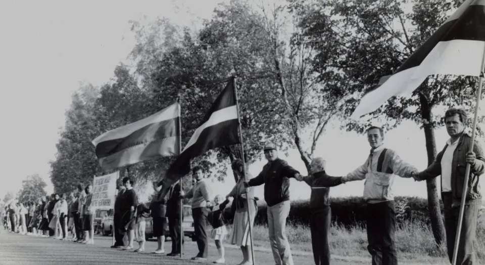 People joining hands and holding Baltic flags during the Baltic Way